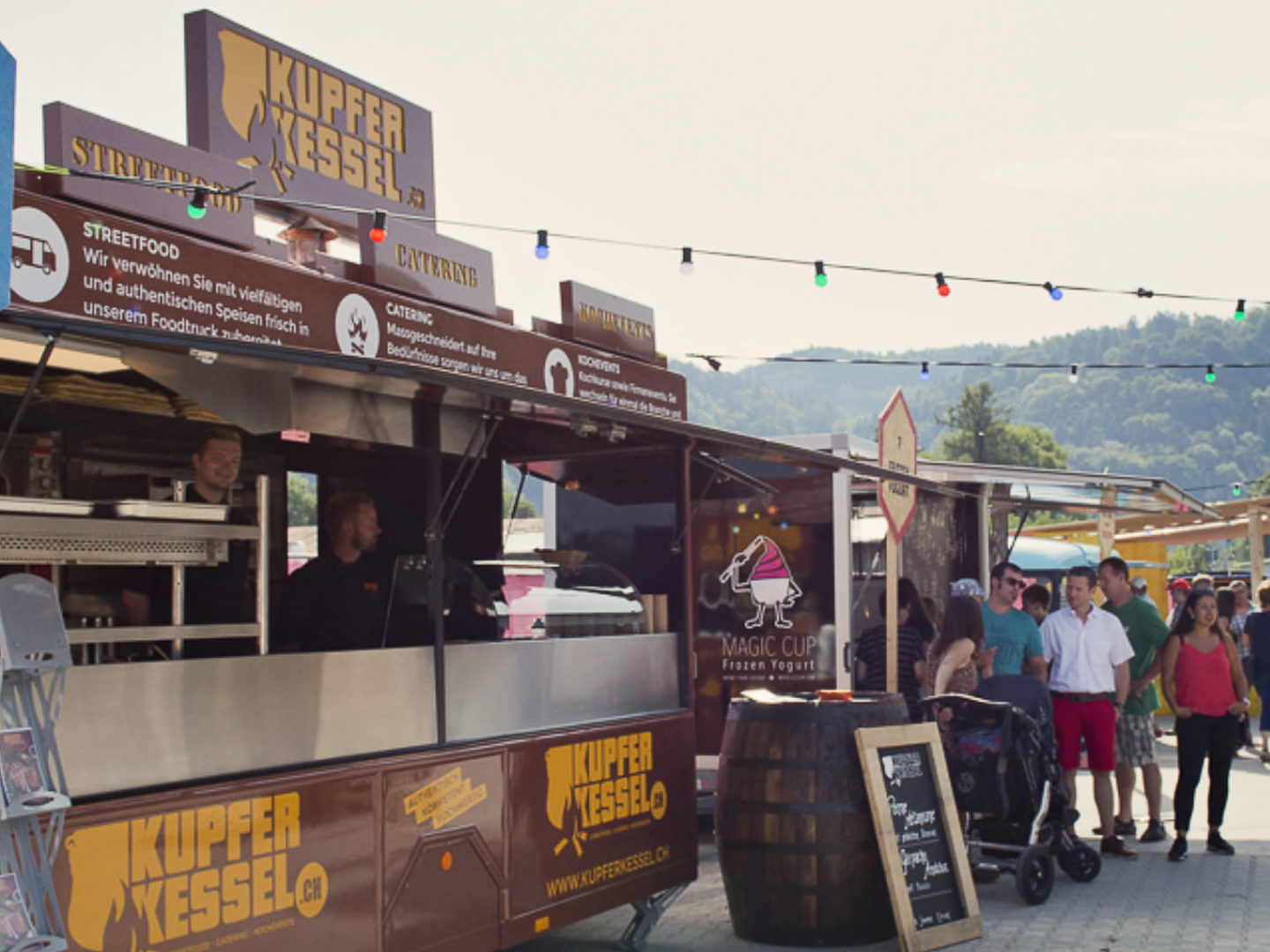 Kupferkessel-Foodtruck mit Gästen an einem Streetfood-Festival unter Lichterketten