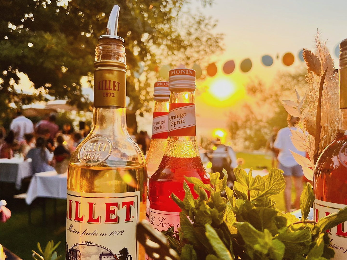 Apéro-Bar mit Lillet-Flaschen vor Gästen im Sonnenuntergang